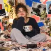 Ritratto editoriale di una giovane creator in una stanza volutamente imperfetta tra camera, cavi e frammenti di immagini